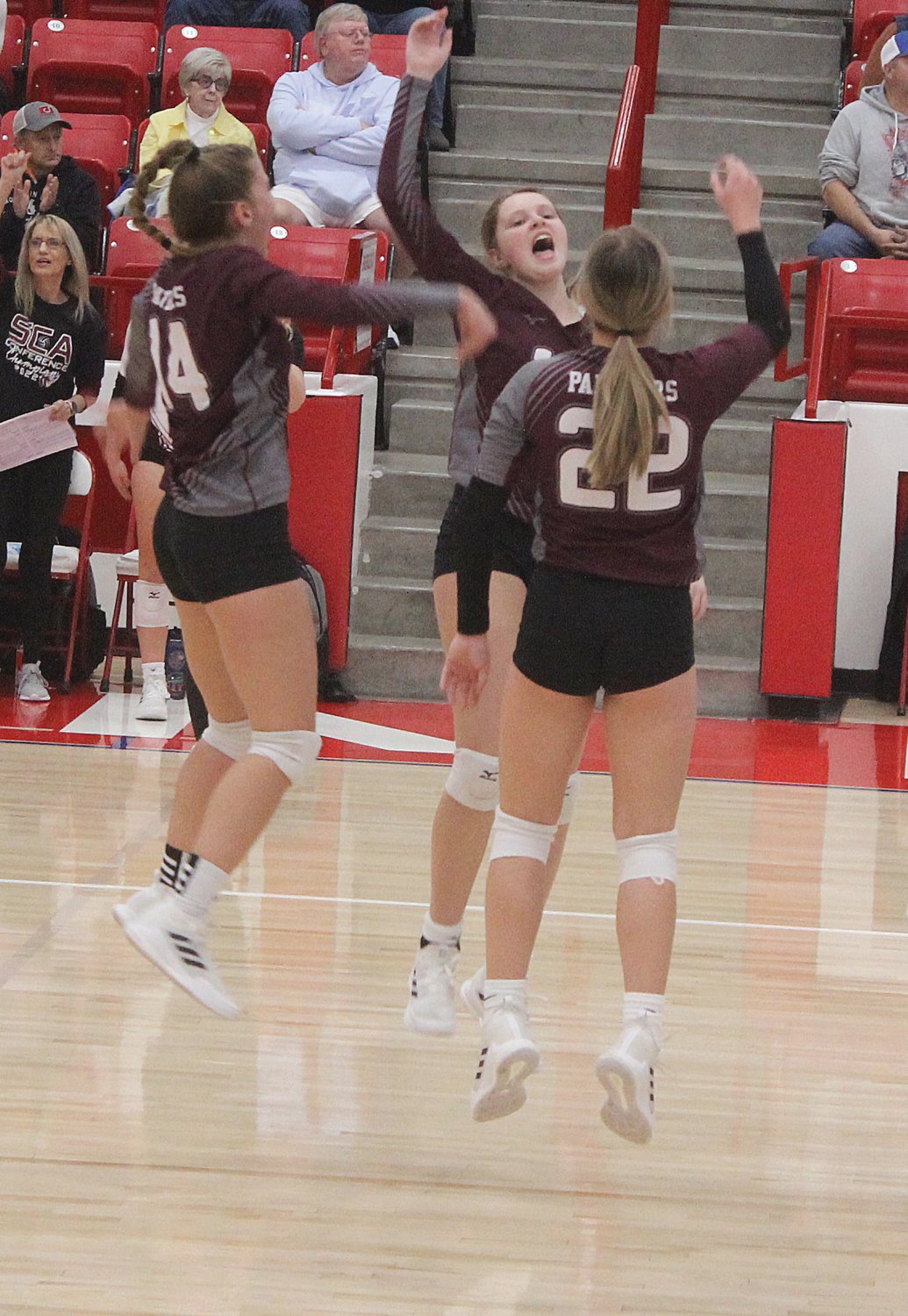 Reagan Hoerning, Erecka Penner and Jozey MacPherson go high in the air to celebrate an ace in sectionals.
